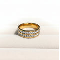 Two gold rings with rows of clear pavé stones, displayed on a soft cream-colored surface against a white background.