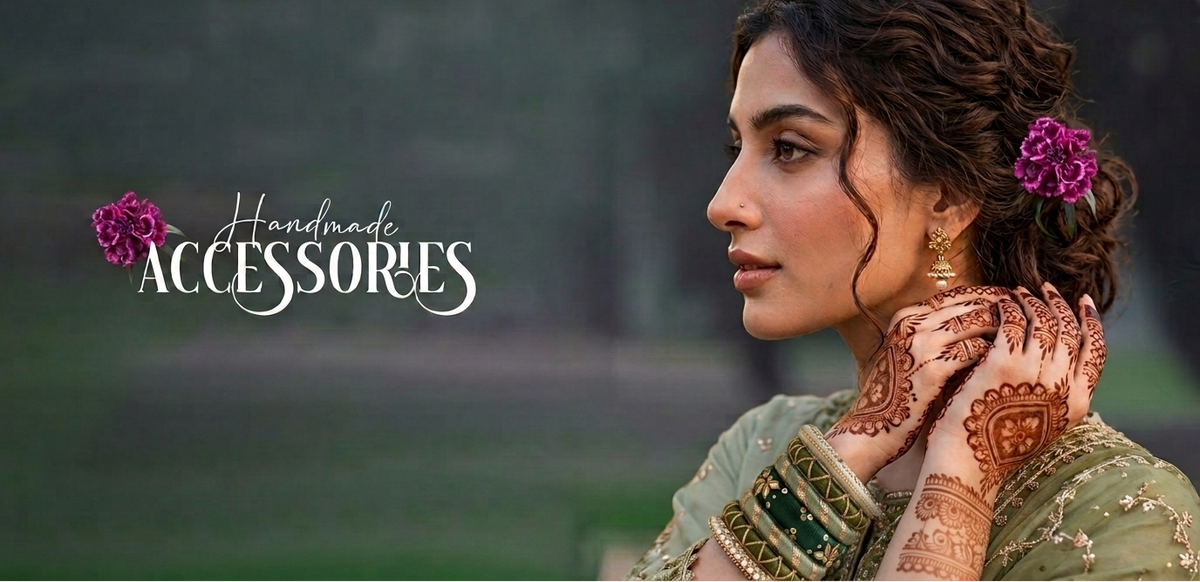 A woman in profile wearing traditional Indian jewelry, including a green embroidered blouse, gold bangles, and earrings, with henna on her hands and purple flowers in her hair. The text 'Handmade ACCESSORIES' appears on the left against a blurred outdoor background.
