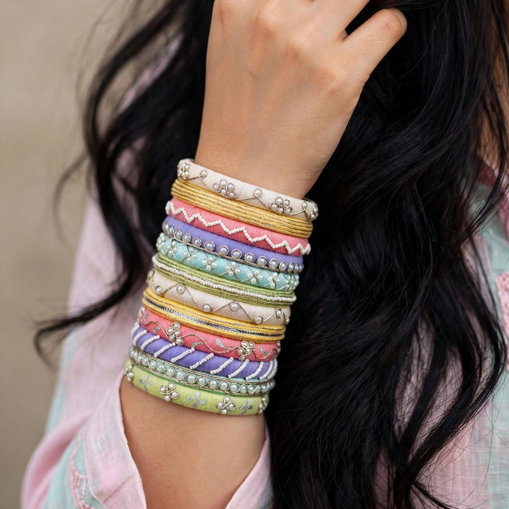 A close-up of a person's wrist wearing a stack of colorful patterned bangles, with long dark hair and a light pink top visible in the background.