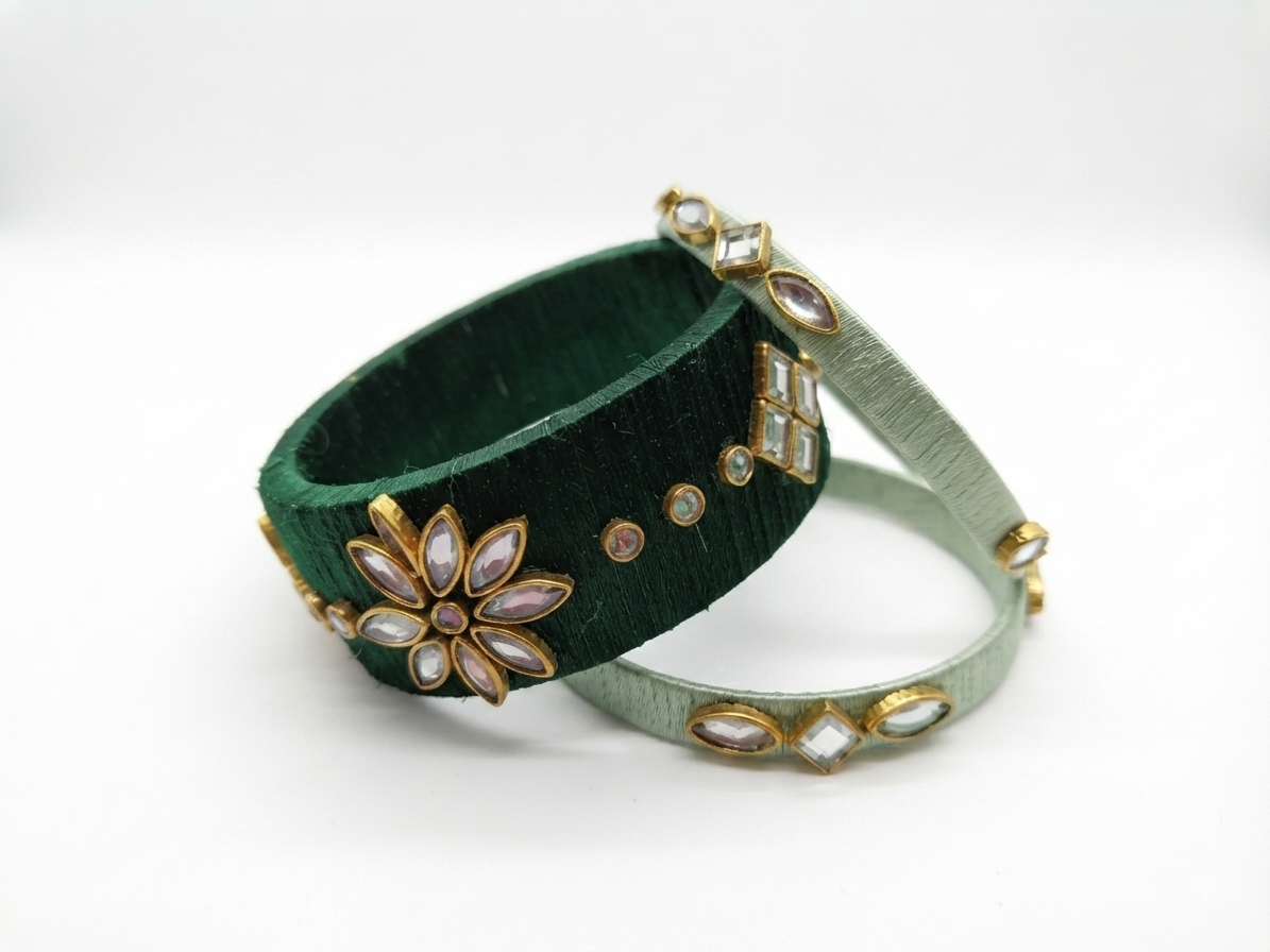 Two traditional Indian Kundan bangles, one dark green velvet with gold floral embellishments and white stones, and the other light sage green with gold and white stone accents, displayed on a white background.