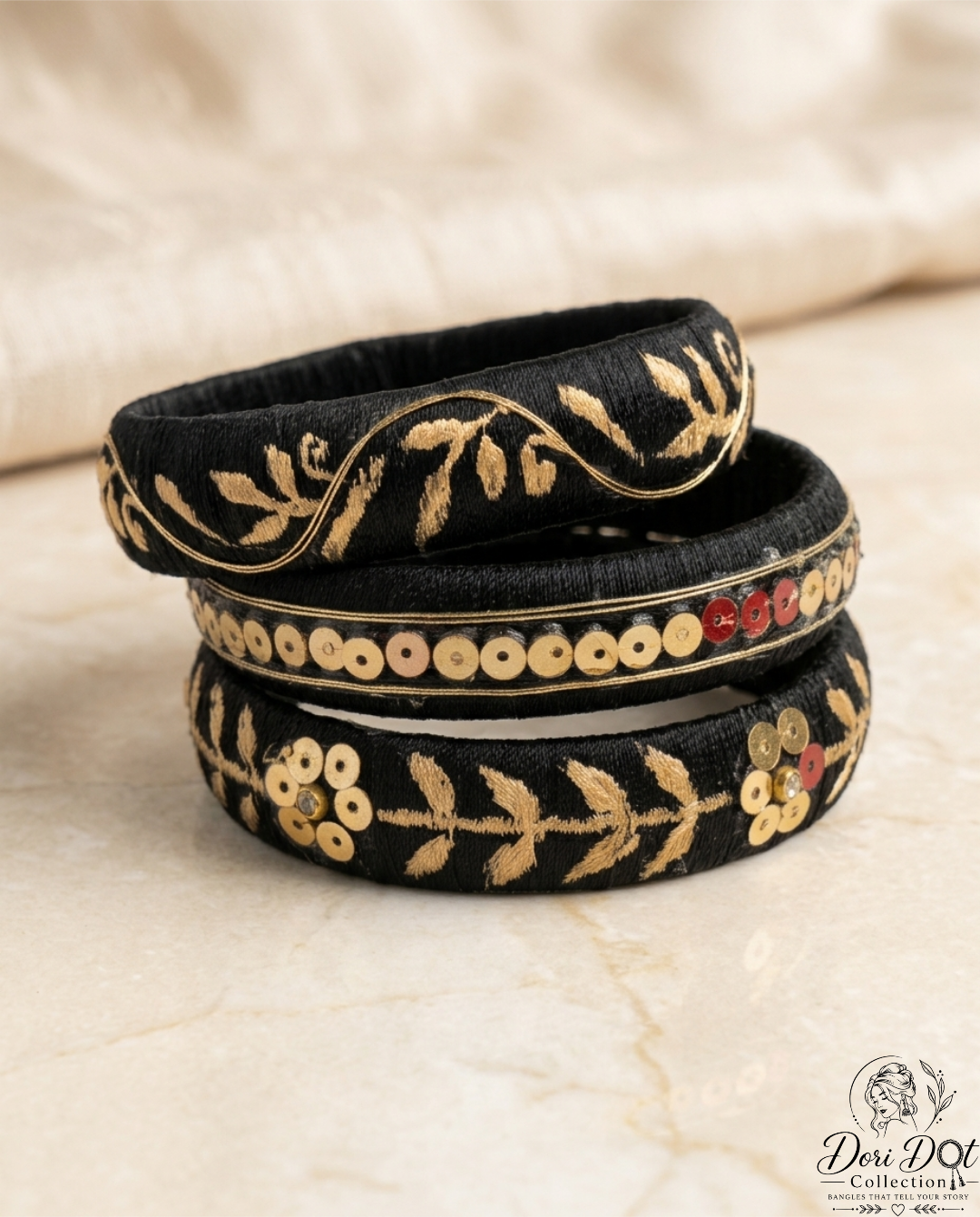 Mehfil collection trio of black silk thread bangles with detailed gold embroidery, sequins, and floral accents by Dori Dot Collection, on a white background.