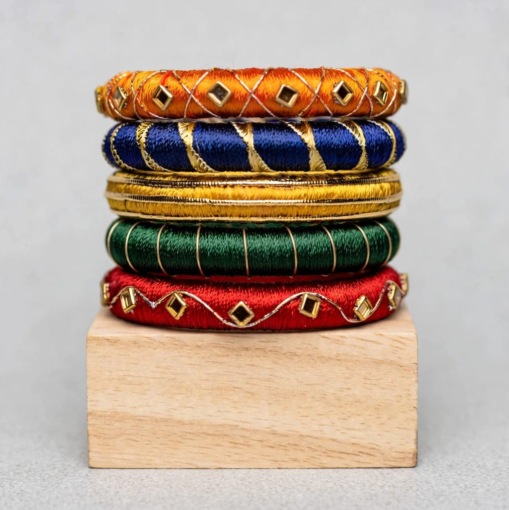 A stack of six colorful woven bangles displayed on a small wooden block against a neutral gray background.