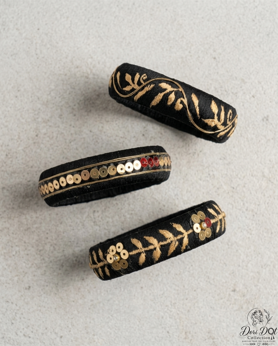 Mehfil collection trio of black silk thread bangles with detailed gold embroidery, sequins, and floral accents by Dori Dot Collection, on a white background.