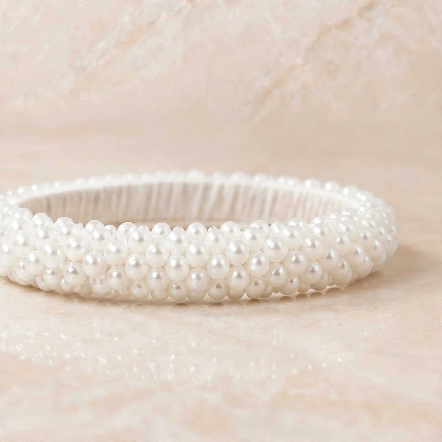 Sitara white pearl beaded handcrafted bangles held in a hand against a lush green outdoor background