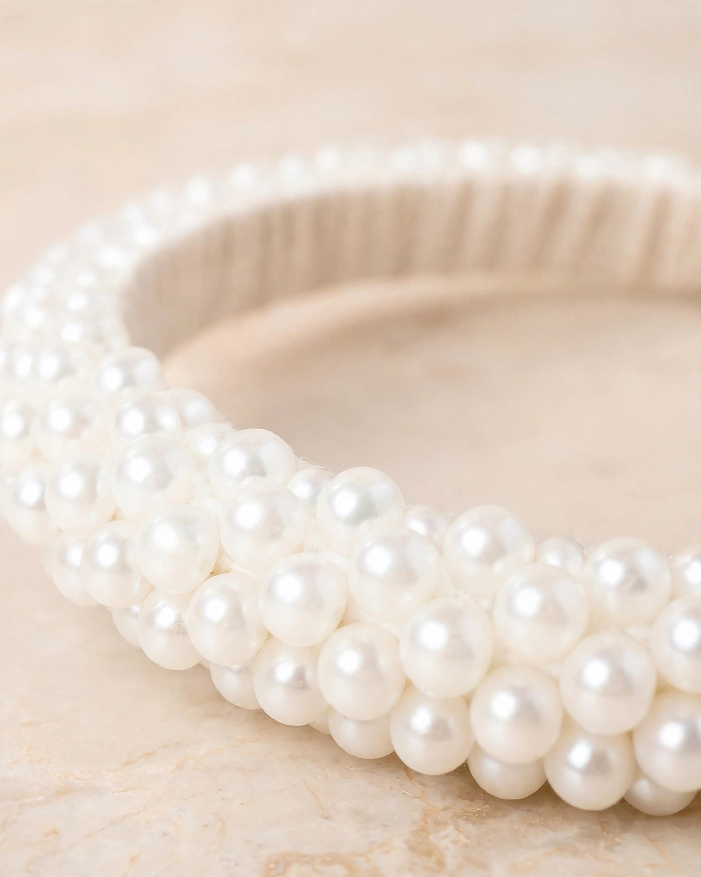 Sitara white pearl beaded handcrafted bangles held in a hand against a lush green outdoor background